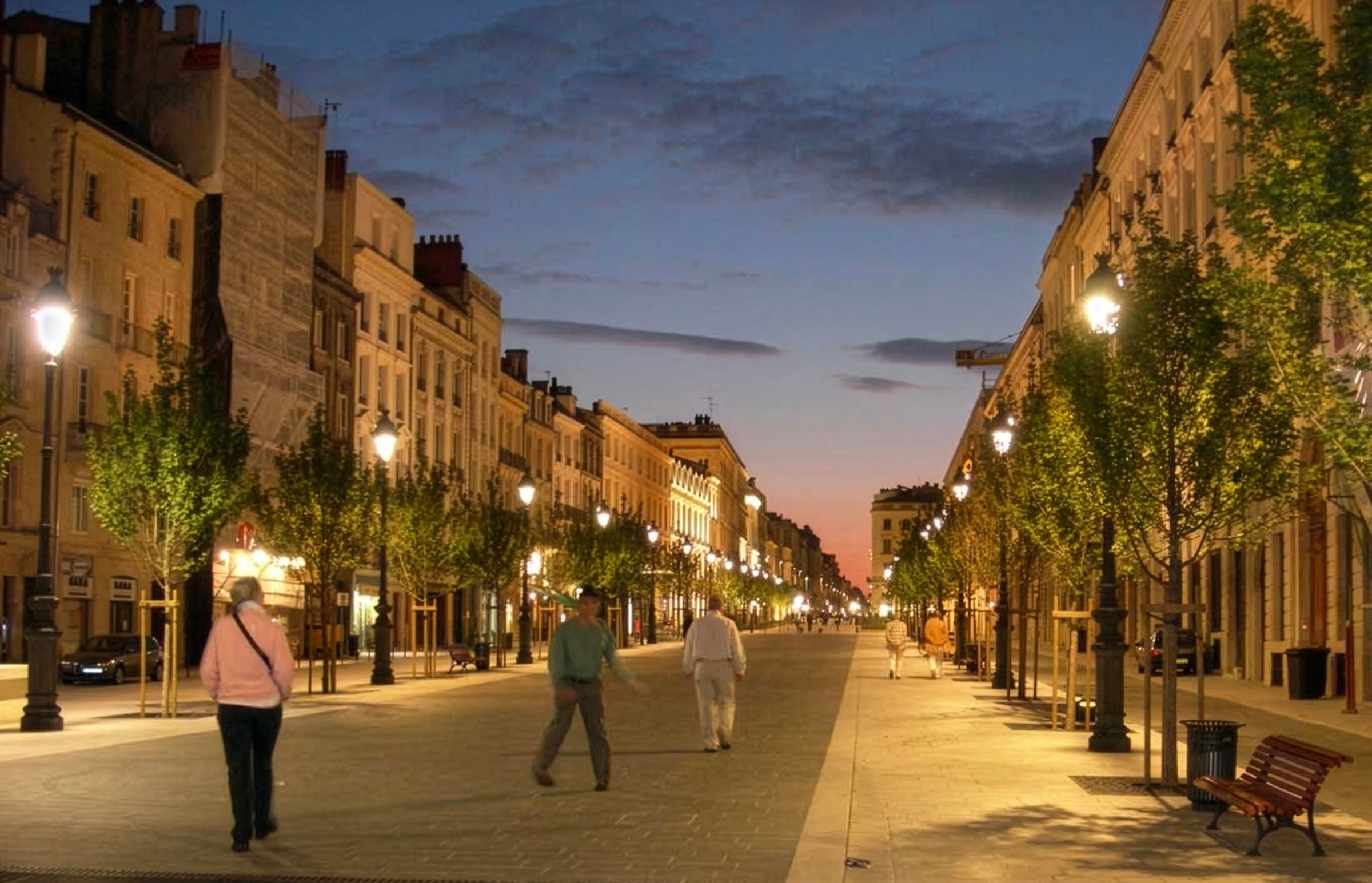 A tree-lined avenue at dusk, where Village Antiques sources pieces in France