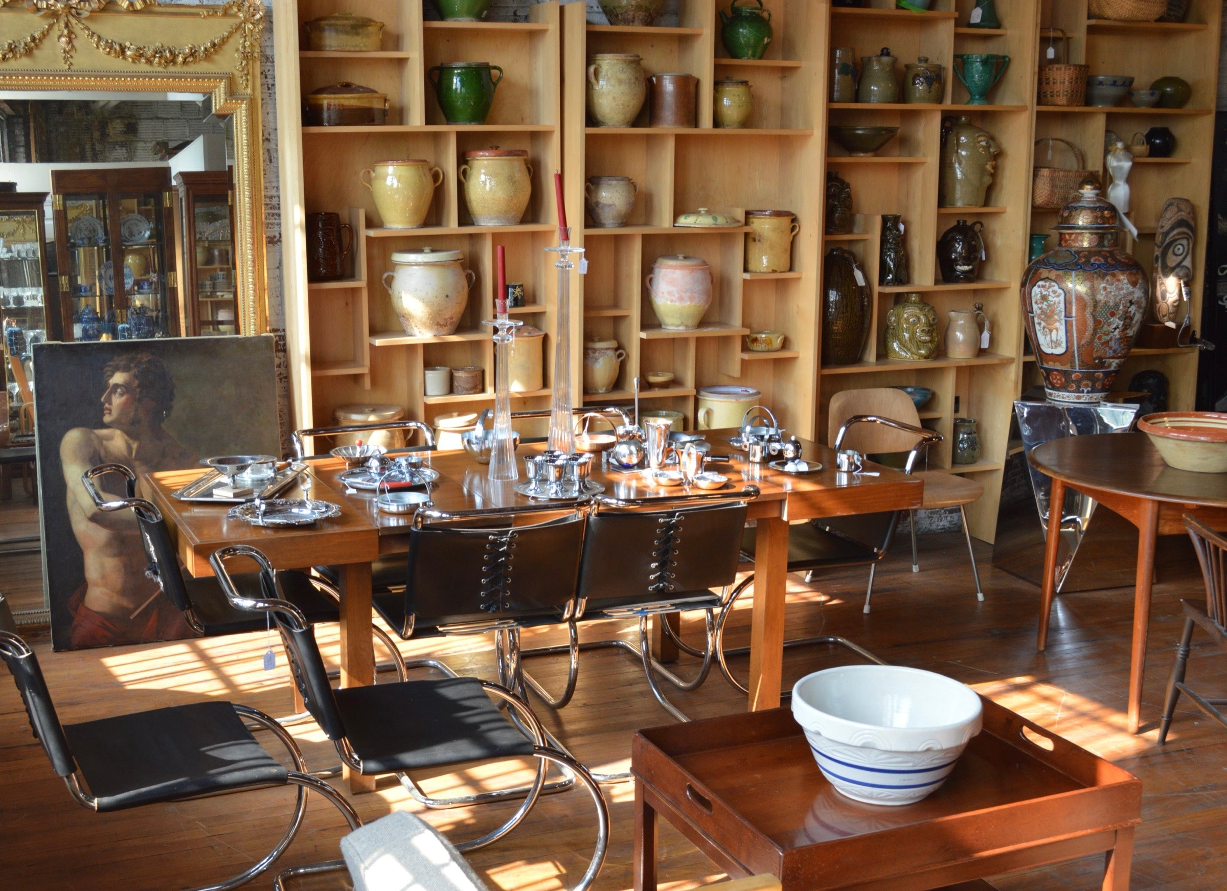 The Village Antiques showroom: a dining table, a gallery wall, and shelves of pottery